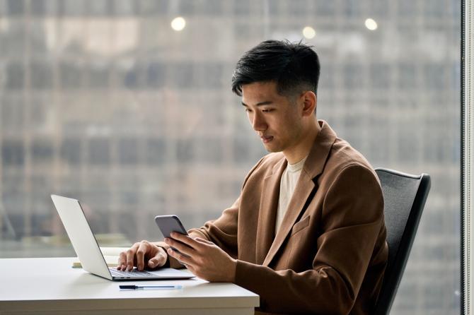 A man trading crypto on his computer and smartphone